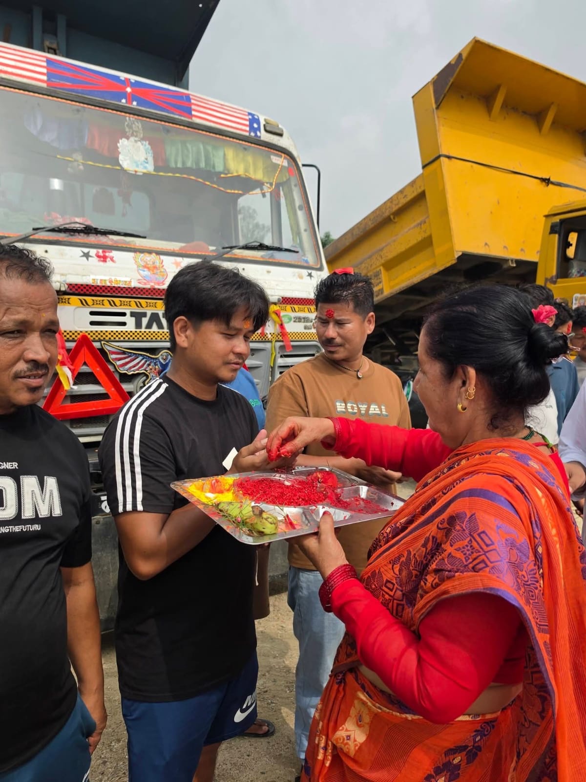 A Nepali site blessing ceremony beside a Puru construction truck